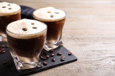 Photo of Glasses of tasty cocktail with coffee beans on wooden table, closeup