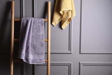 Photo of Soft terry towels and wooden ladder indoors, space for text