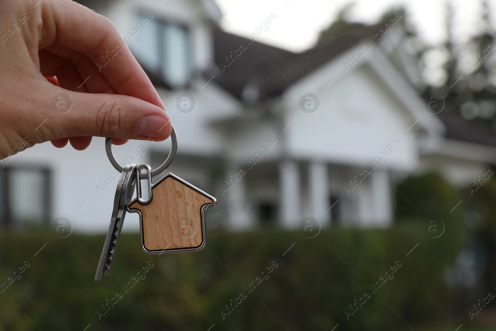 Photo of Woman holding house keys outdoors, closeup with space for text. Real estate agent