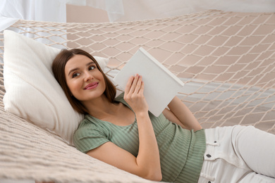 Photo of Happy woman with book in hammock at home