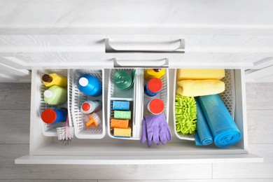 Photo of Different cleaning supplies in open drawer indoors, top view