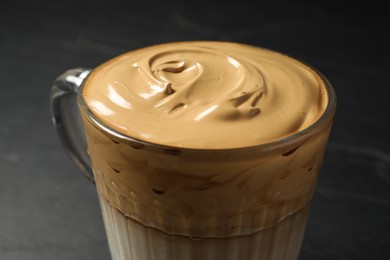 Photo of Glass mug of delicious dalgona coffee on dark background, closeup