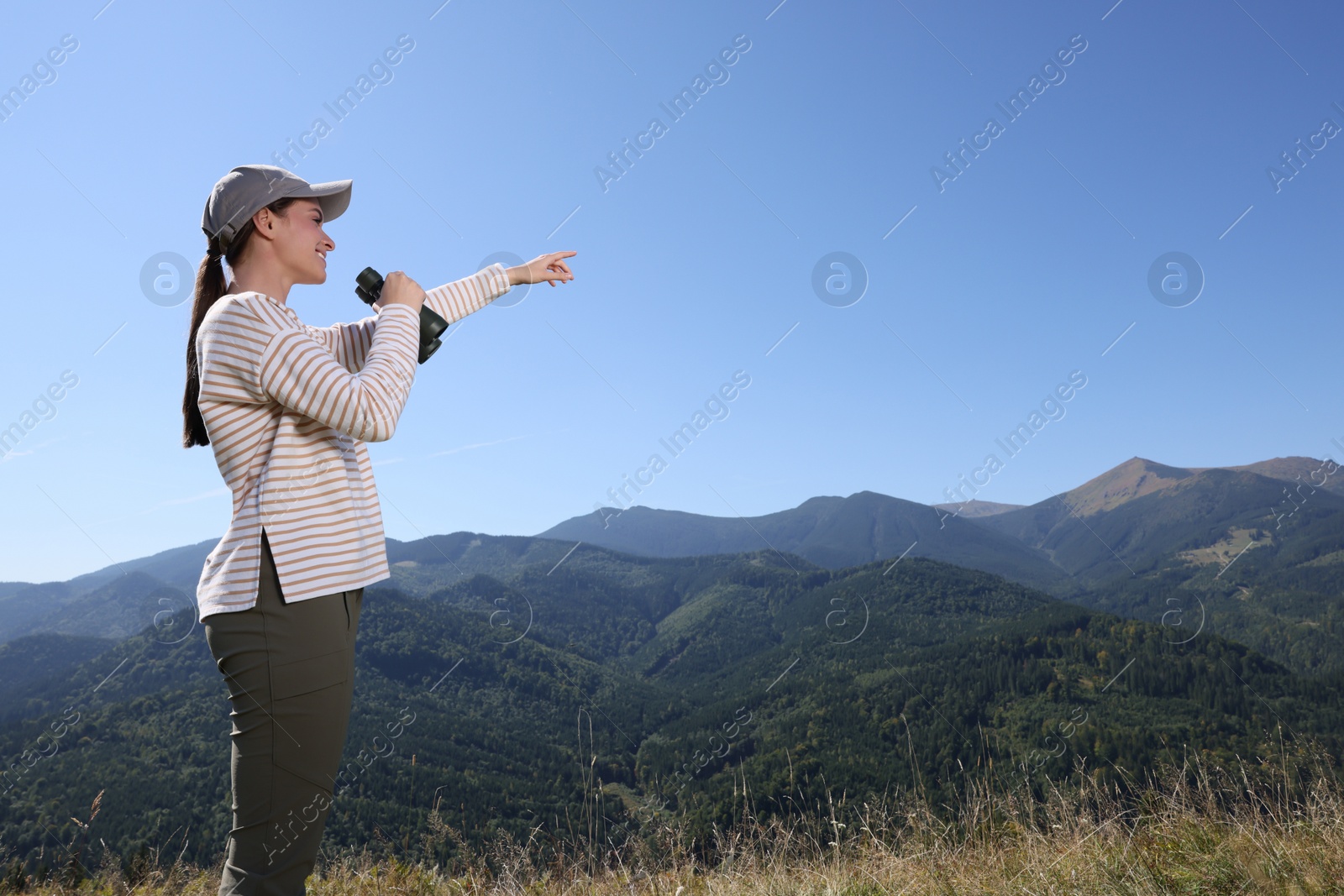 Photo of Woman with binoculars in mountains on sunny day