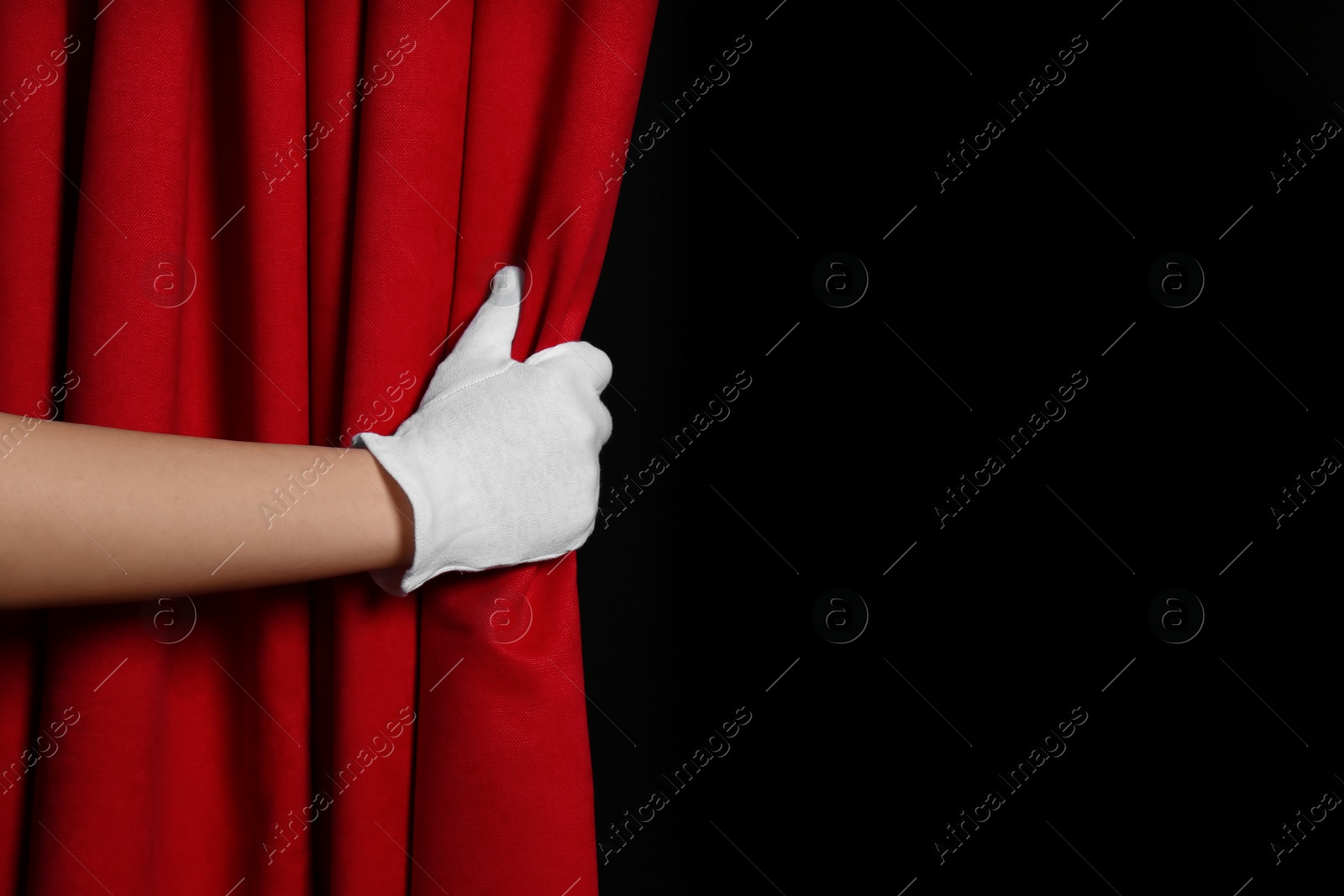 Photo of Woman opening red front curtains on black background, closeup. Space for text