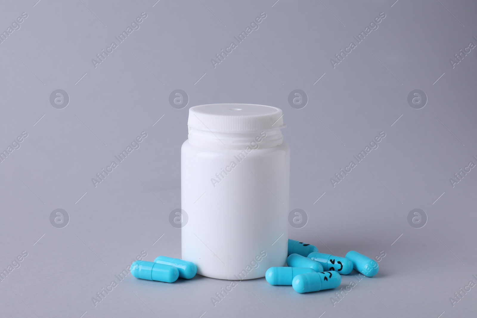 Photo of Antidepressants with happy emoticons and medical jar on light grey background