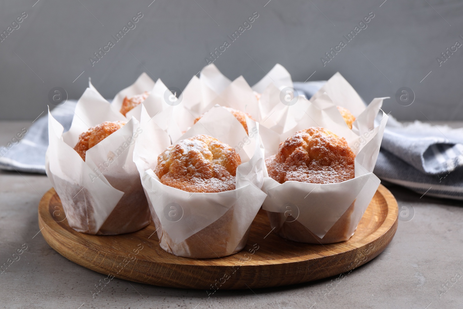 Photo of Delicious muffins with powdered sugar on grey table