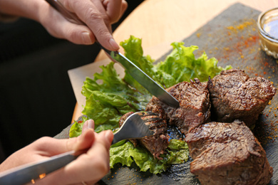 Woman eating tasty shish kebab in cafe