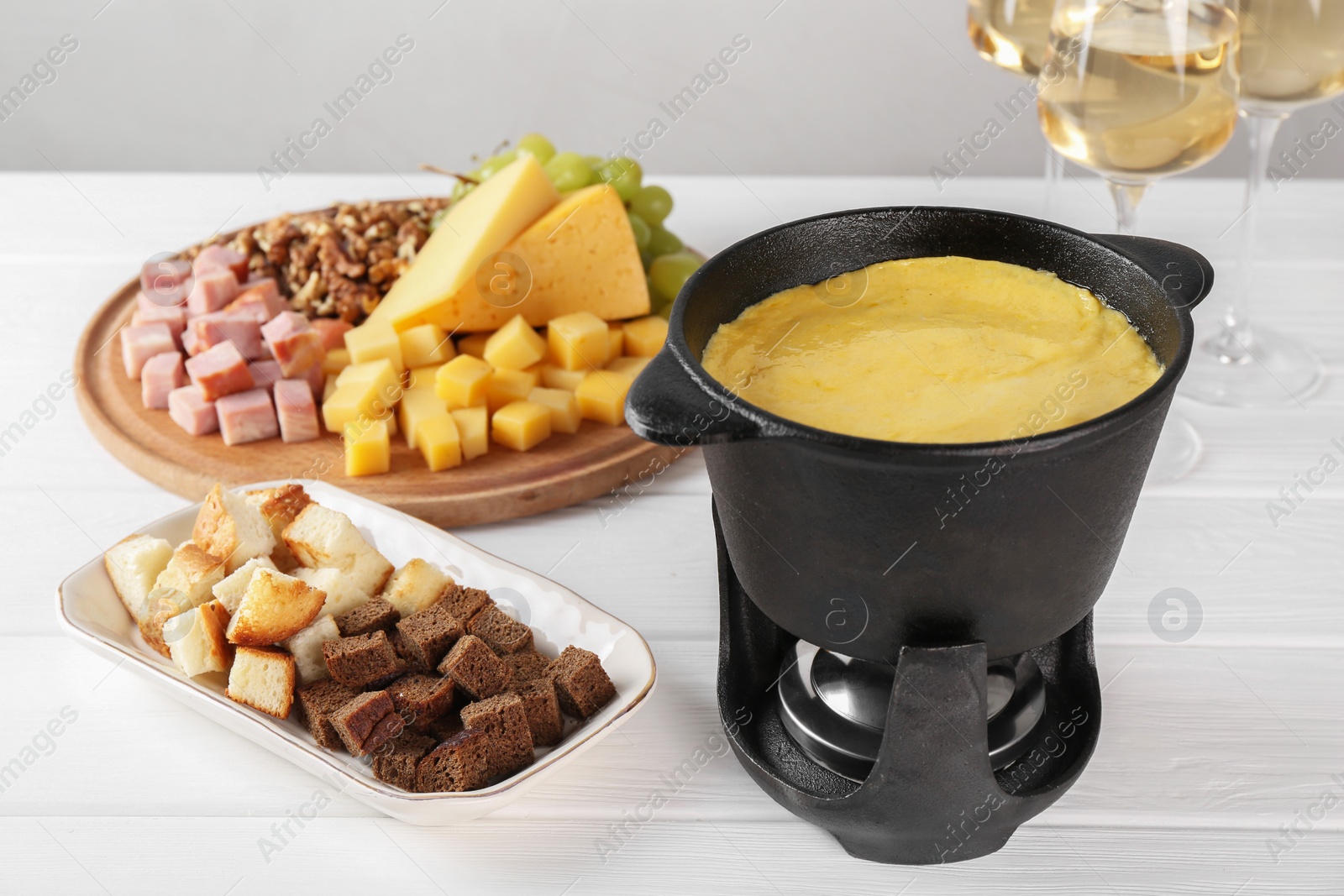 Photo of Fondue with tasty melted cheese and different products white wooden table