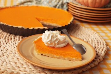 Piece of fresh homemade pumpkin pie with whipped cream on table