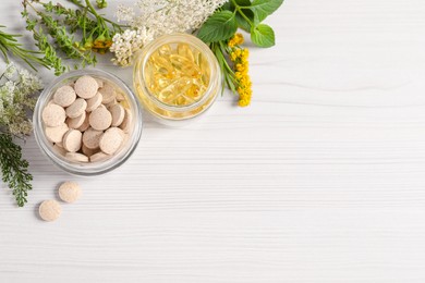 Different pills, flowers and herbs on white wooden table, flat lay with space for text. Dietary supplements