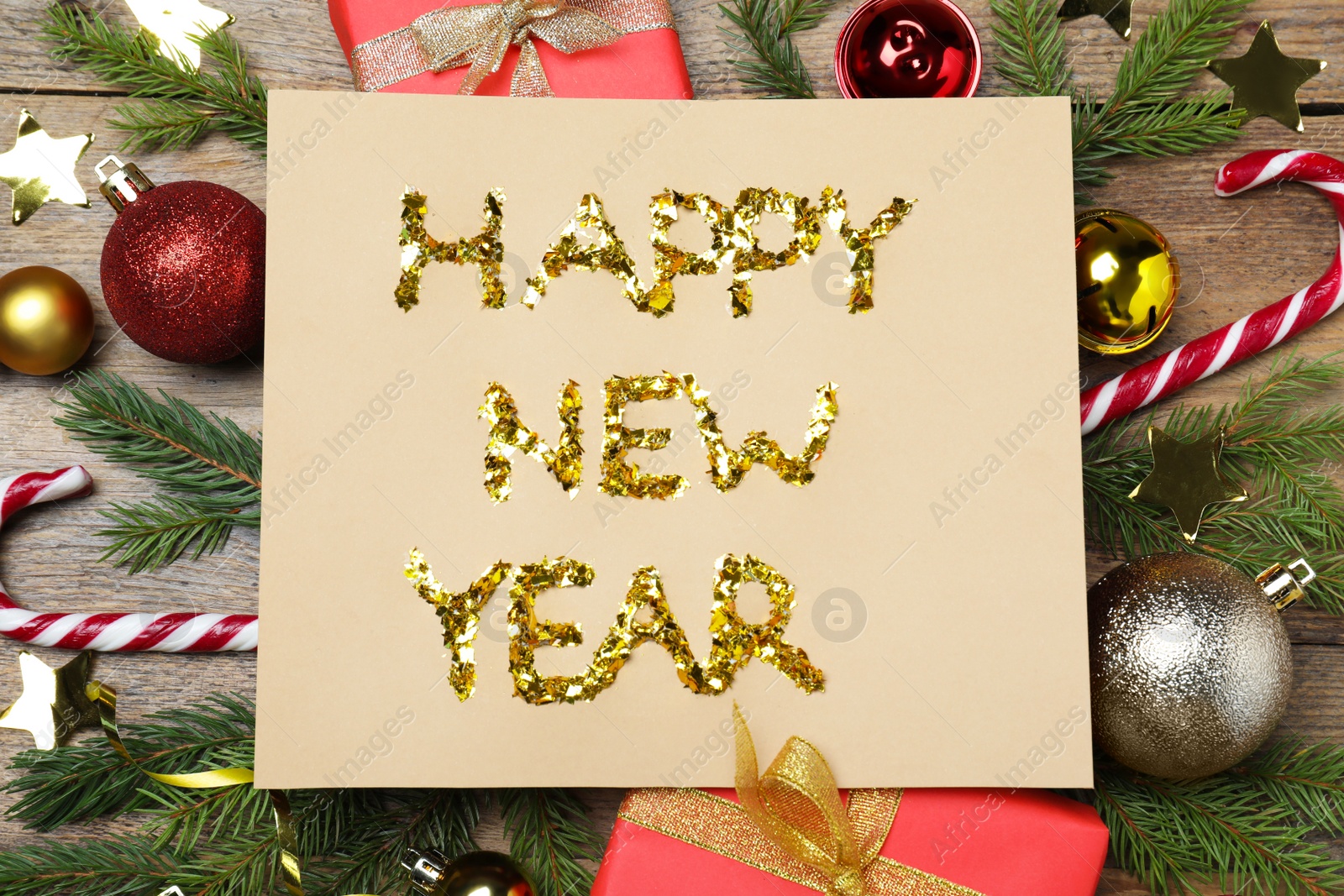 Photo of Card with phrase Happy New Year and festive decor on wooden background, flat lay