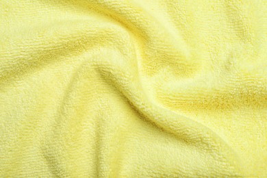 Photo of Crumpled pale yellow microfiber cloth as background, closeup