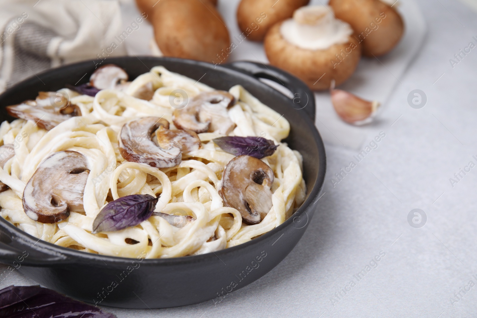 Photo of Delicious pasta with mushrooms on grey table, closeup