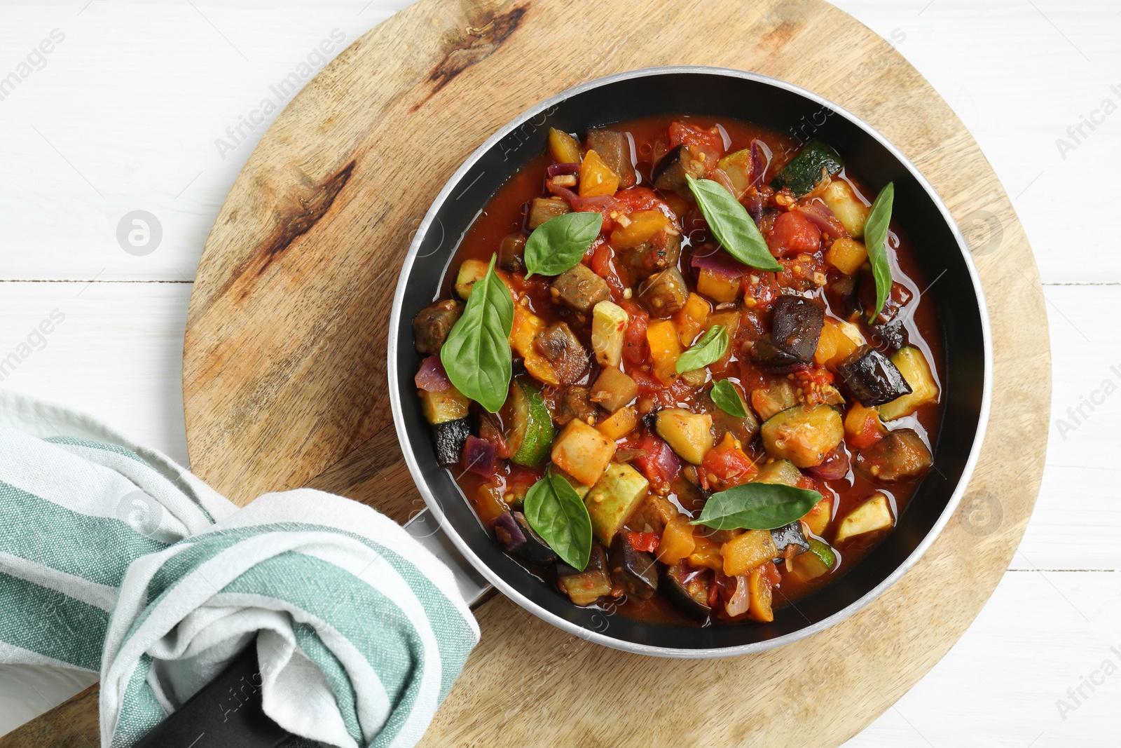 Photo of Frying pan with tasty ratatouille on white wooden table, top view