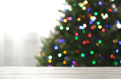 Photo of Empty table and blurred fir tree with colorful Christmas lights on background, bokeh effect. Space for design