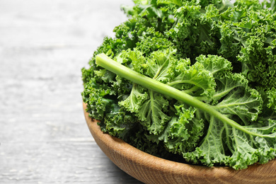 Fresh kale leaves on light grey wooden table, closeup