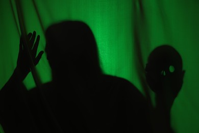 Photo of Silhouette of creepy ghost with skull behind dark green cloth