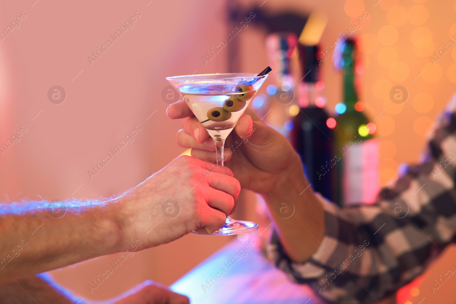 Photo of Young man taking martini cocktail from barman in pub, closeup