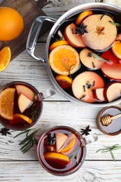 Photo of Tasty mulled wine with spices on white wooden table, flat lay