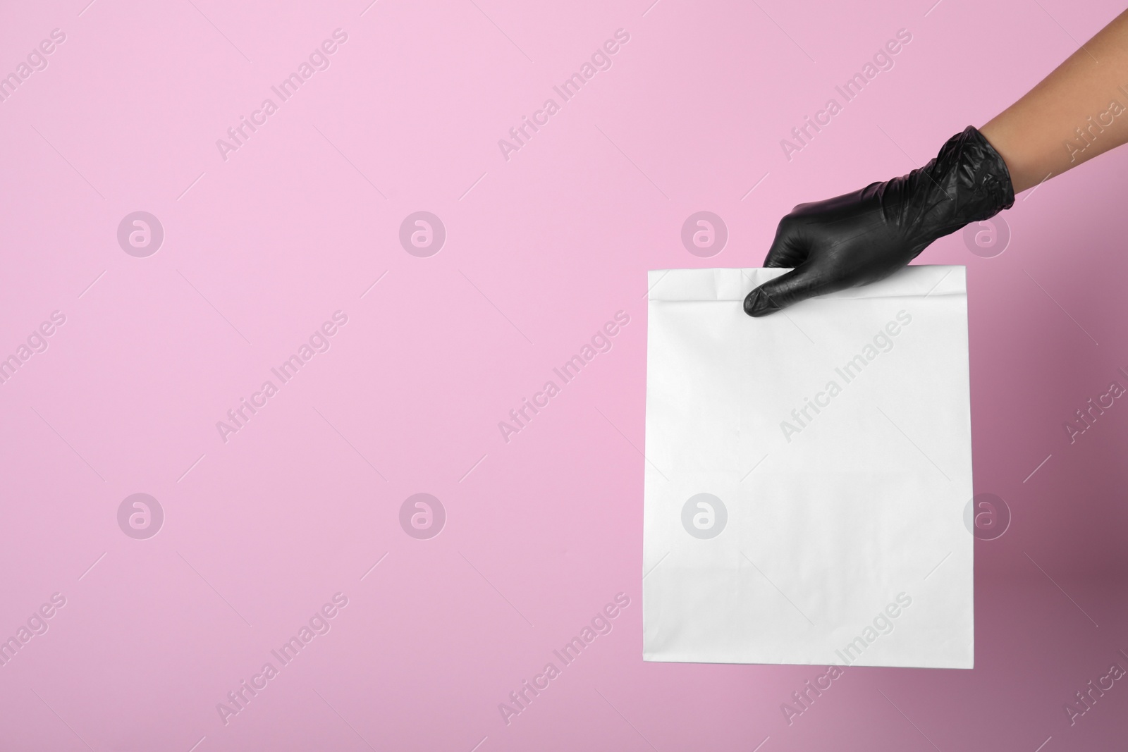 Photo of Woman holding paper bag on pink background, closeup. Space for text