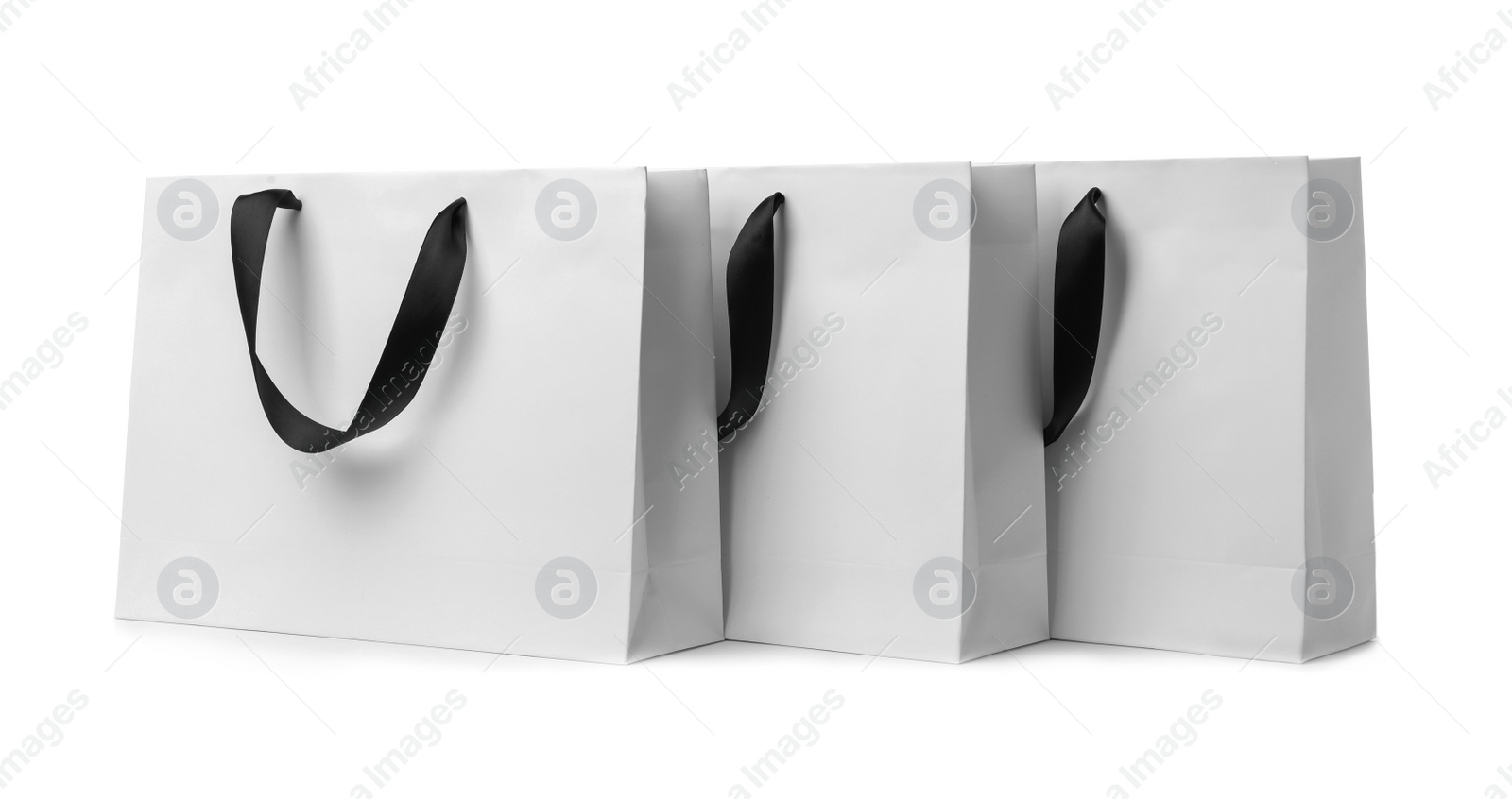 Photo of Paper shopping bags with ribbon handles on white background. Mockup for design