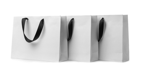 Photo of Paper shopping bags with ribbon handles on white background. Mockup for design