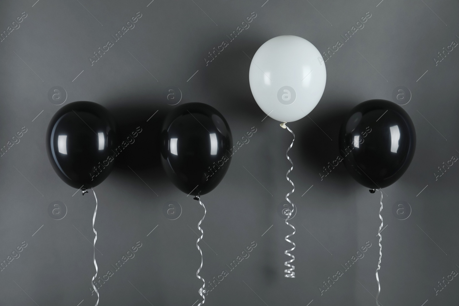 Photo of White balloon rising higher than others on black background. Be different