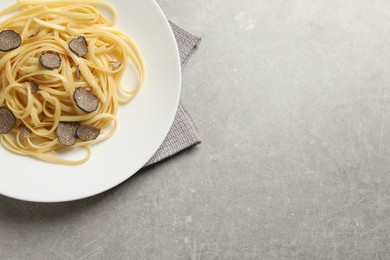 Tasty fettuccine with truffle on grey table, top view. Space for text