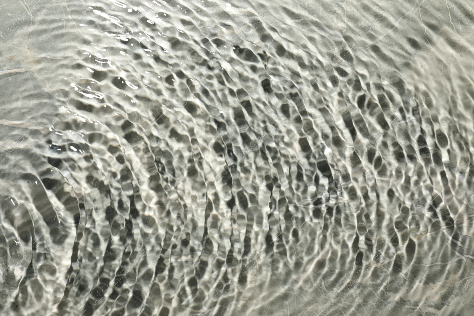 Photo of Rippled surface of clear water on light grey textured background, top view