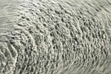 Rippled surface of clear water on light grey textured background, top view