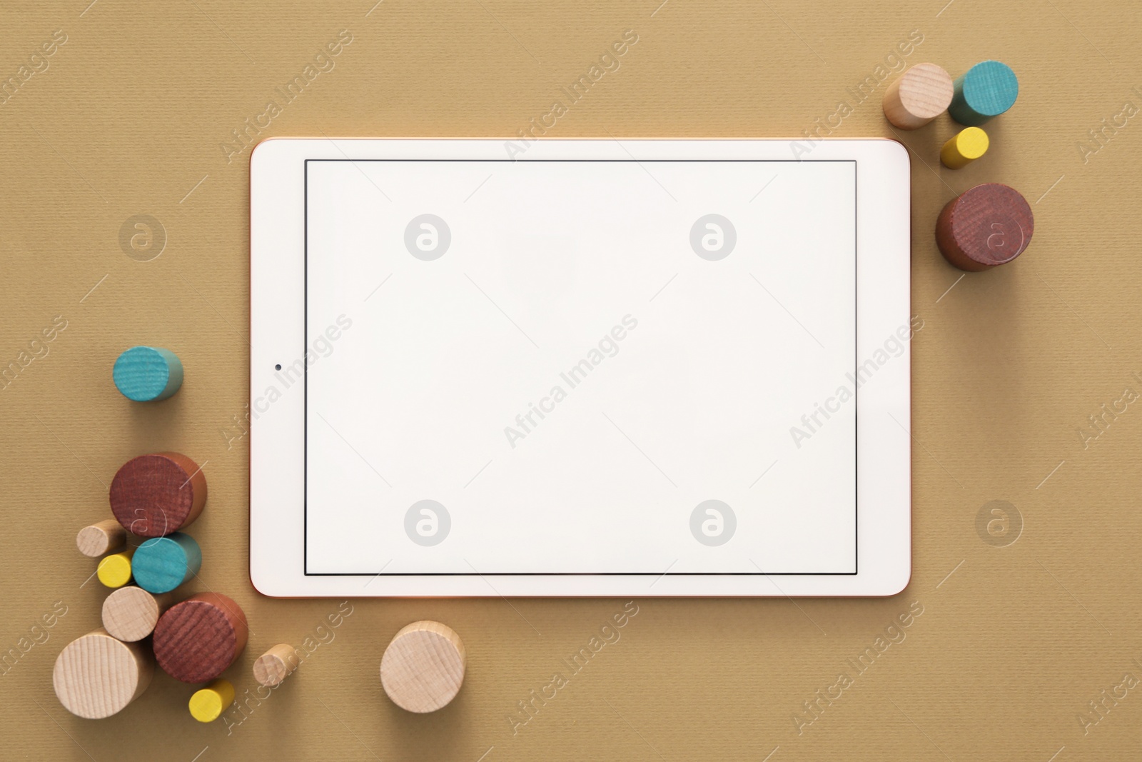 Photo of Modern tablet and wooden toys on brown background, flat lay. Space for text