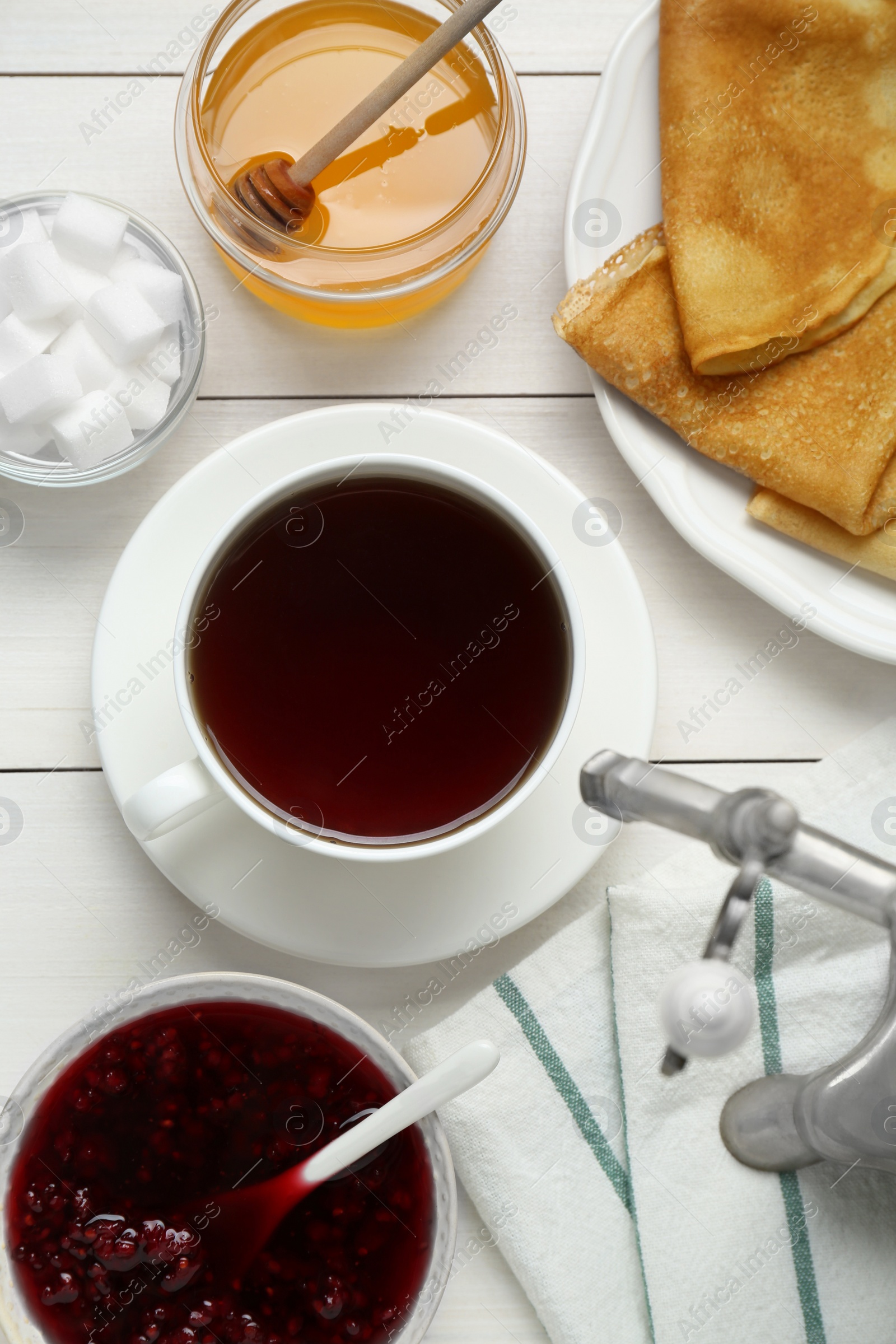 Photo of Metal samovar with cup of tea and treats on white wooden table, flat lay