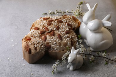 Photo of Delicious Italian Easter dove cake (Colomba di Pasqua), flowers and bunny figures on grey table
