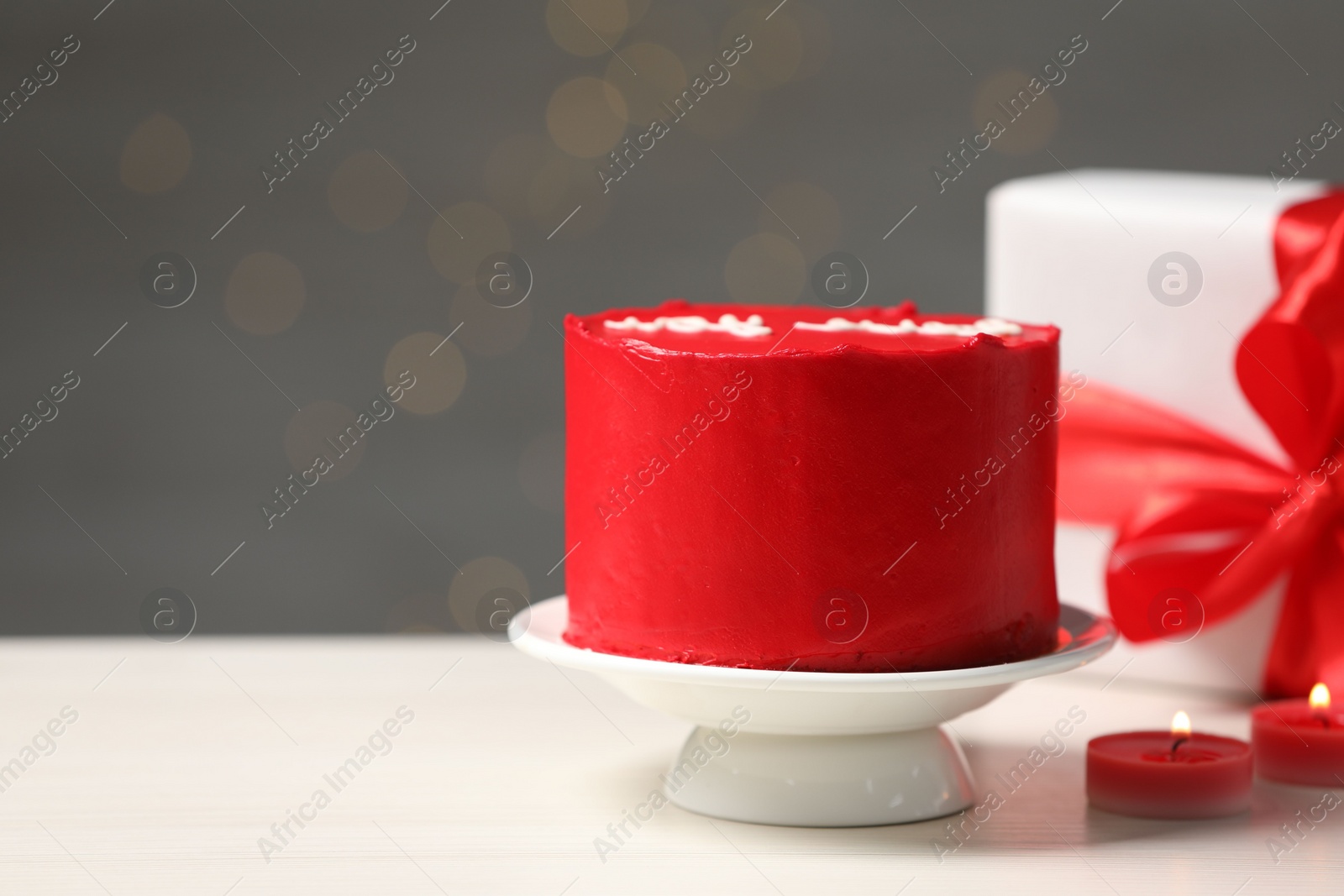 Photo of Bento cake, gift box and candles on white wooden table, space for text. St. Valentine's day surprise