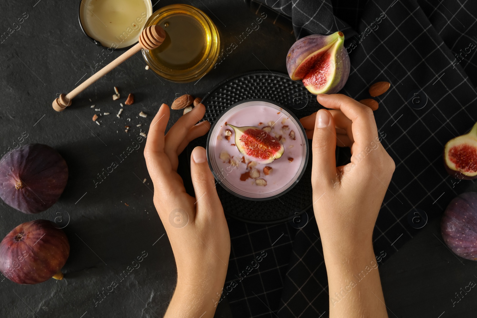 Photo of Woman with delicious fig smoothie at black table, top view