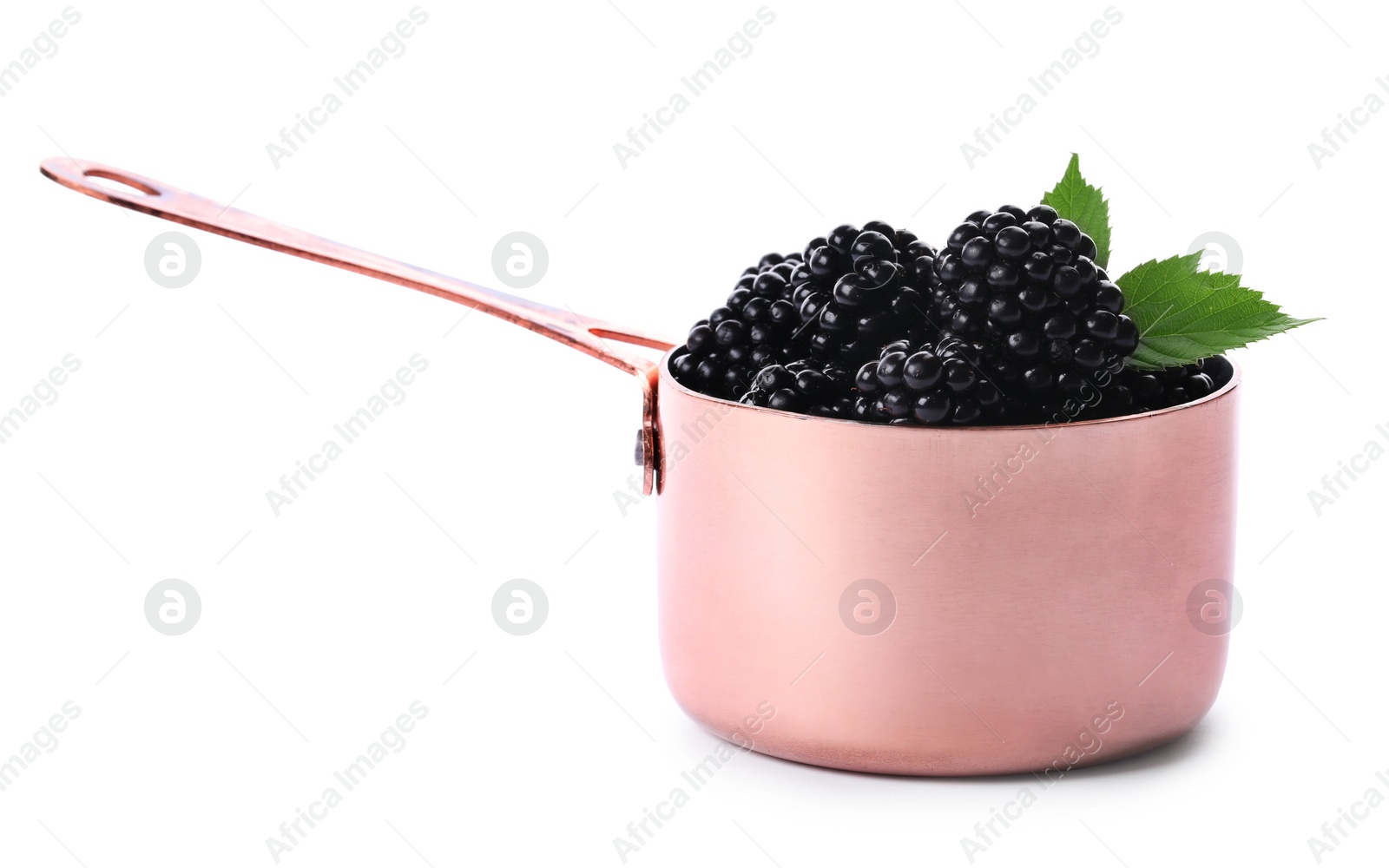 Photo of Metal sauce pan with tasty blackberries and leaves on white background