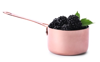 Photo of Metal sauce pan with tasty blackberries and leaves on white background