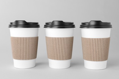 Photo of Paper cups with black lids on light grey background. Coffee to go