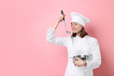 Photo of Professional chef cooking pot and ladle on pink background. Space for text