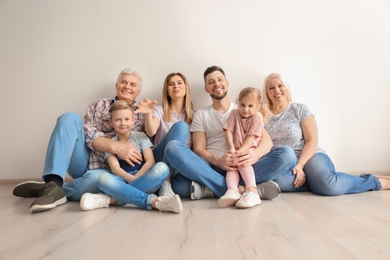 Photo of Happy family with cute kids sitting on floor near light wall