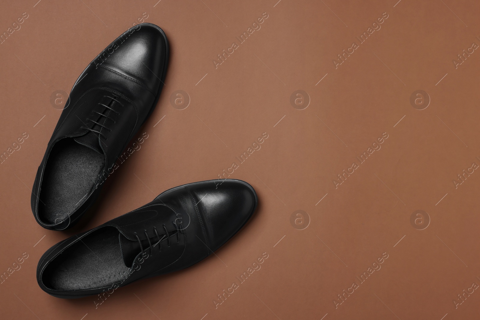 Photo of Pair of leather men shoes on brown background, top view. Space for text