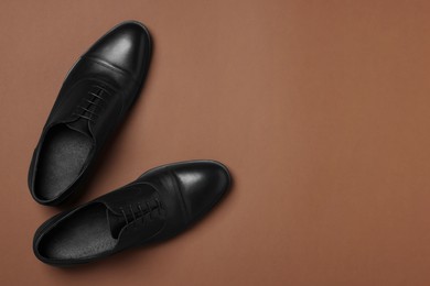 Pair of leather men shoes on brown background, top view. Space for text