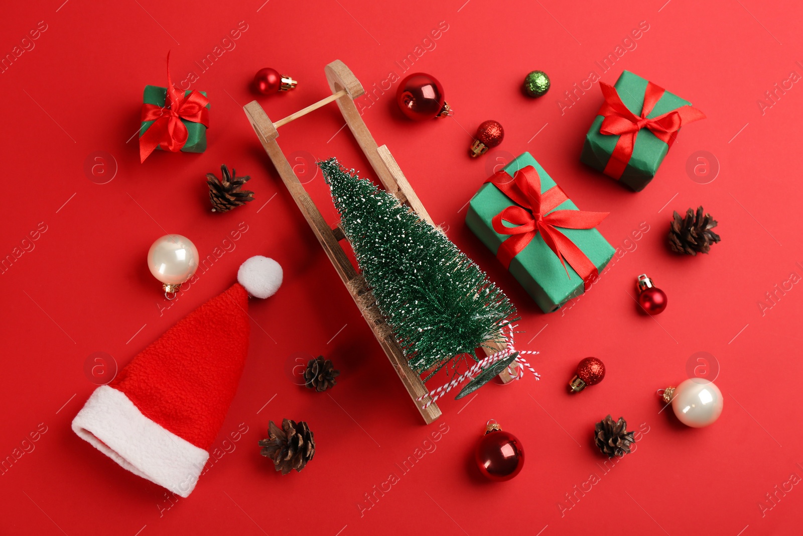 Photo of Beautiful Christmas composition with miniature sleigh on red background, flat lay