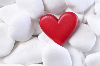 Photo of Decorative heart on white pebble stones, top view