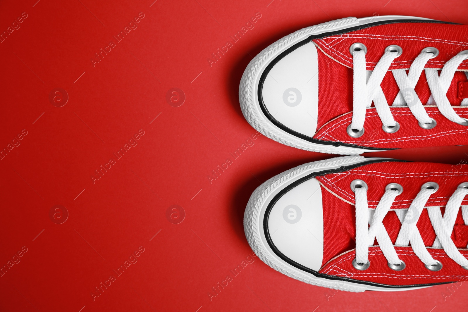 Photo of Pair of new stylish sneakers on red background, flat lay. Space for text