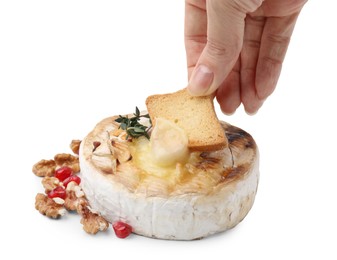 Woman dipping crouton into tasty baked camembert on white background, closeup
