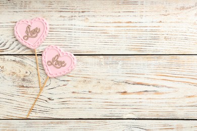 Chocolate heart shaped lollipops with word Love on white wooden table, flat lay. Space for text