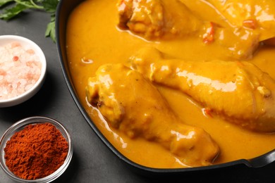 Photo of Tasty chicken curry and ingredients on black table, closeup