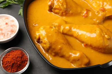 Tasty chicken curry and ingredients on black table, closeup