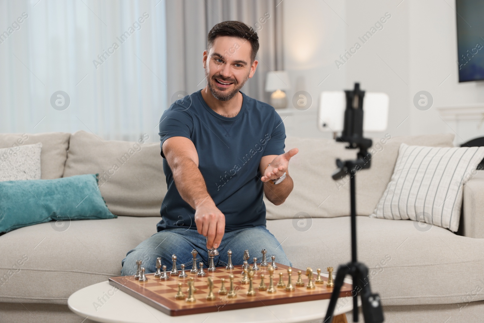 Photo of Teacher near chessboard conducting online lesson at home. Time for hobby